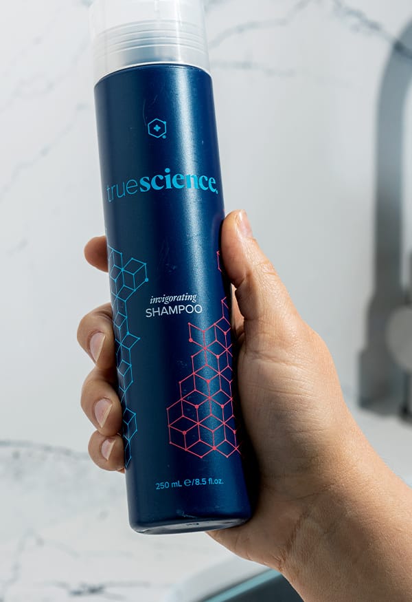 Person holding TrueScience Shampoo for clarifying hair