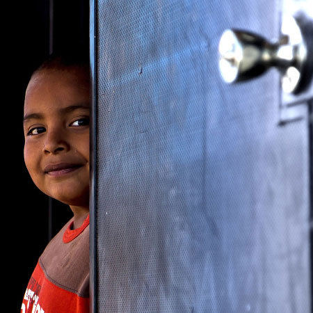Young boy looking through a door