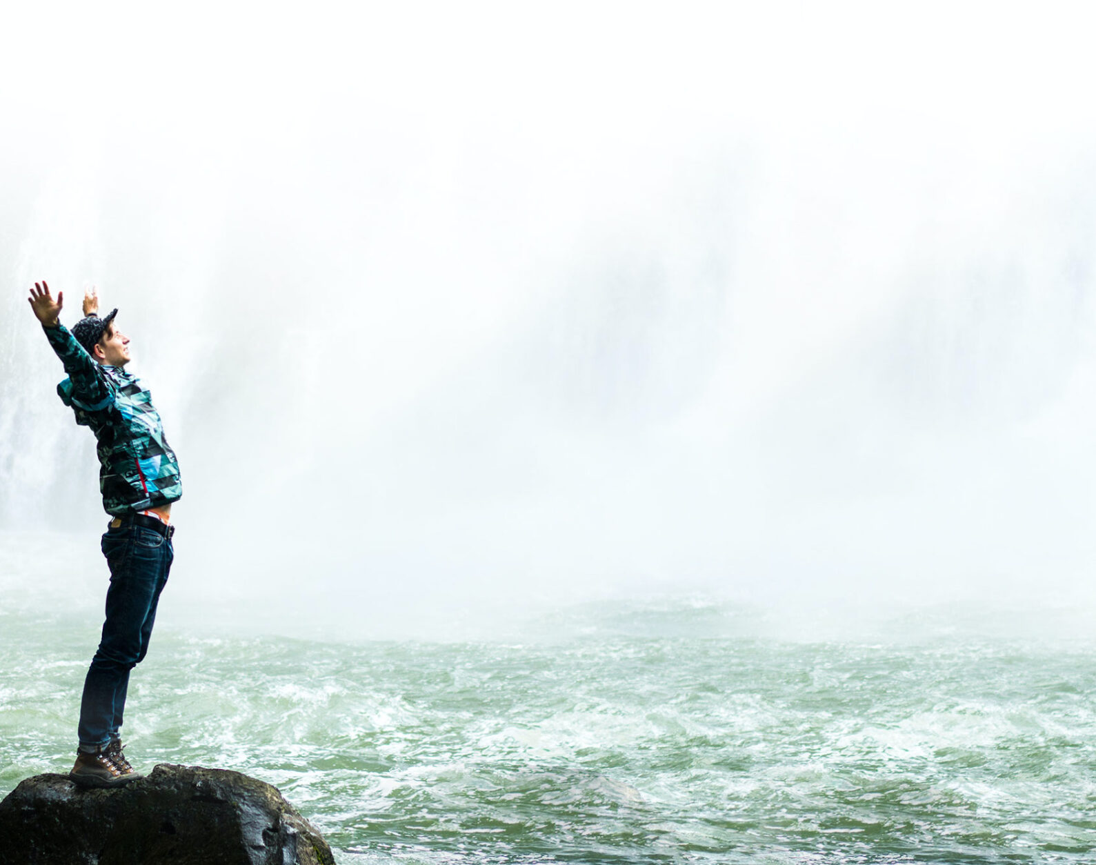 Man With Arms Open at Bottom of Waterfall